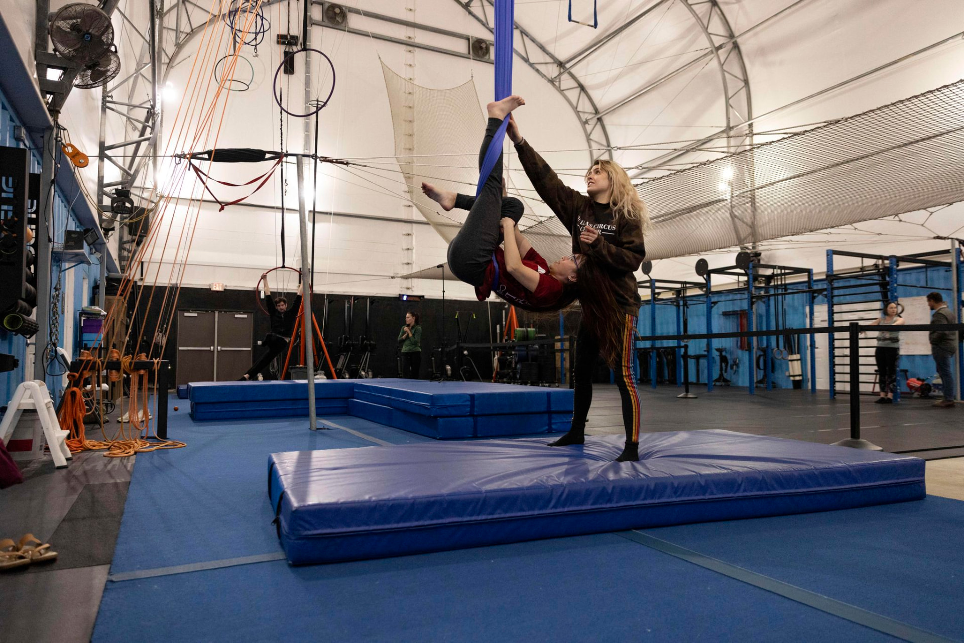 Coach spotting a student as she trains on an aerial hammock at Dallas Circus Center
